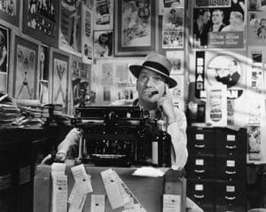 Check out this vintage journalist... smokin' a cigar in the office.
