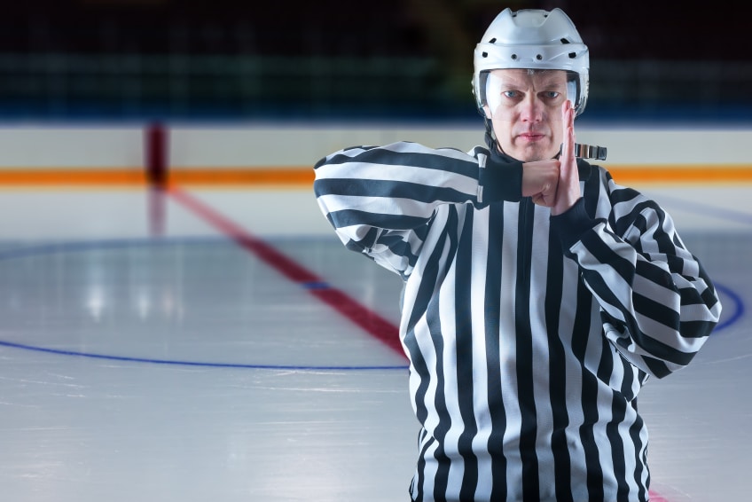 Hockey referree demonstrate boarding penalty. Ice rink on background